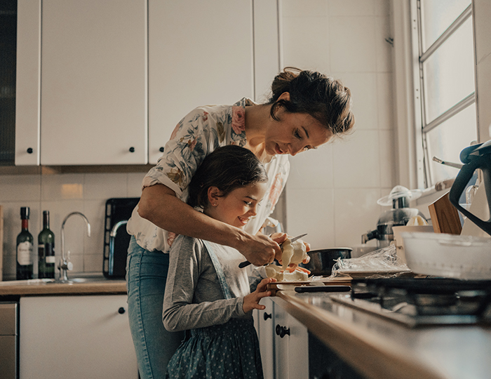 Woman cutting apple in kitchen with daughter